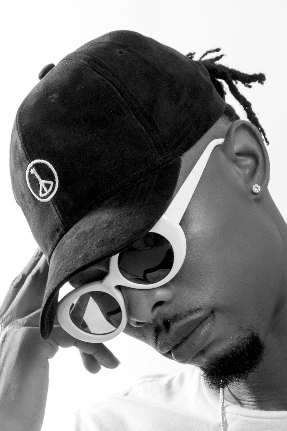 Andre Blunt black cap with embroidered wheel of peace, worn side profile