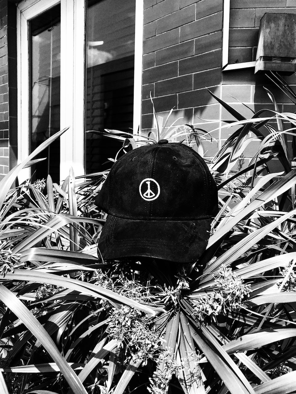 Andre Blunt black cap with embroidered wheel of peace