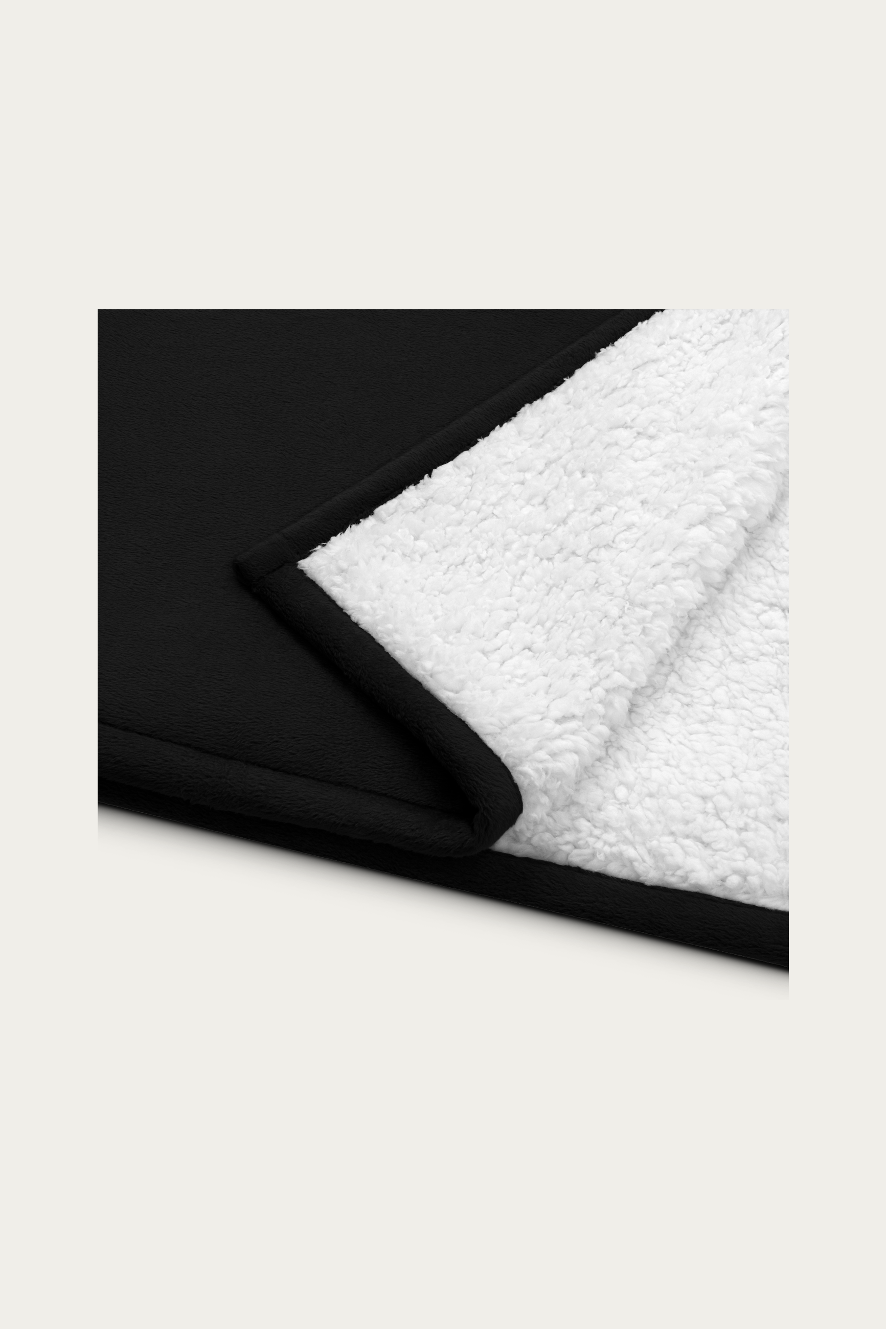 Sherpa Blanket, Black by Andre Blunt, folded corner showing the sherpa reverse, on a Cloud White ground